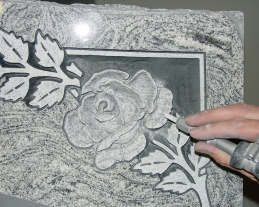 using a tool to finish the rose design in the stone